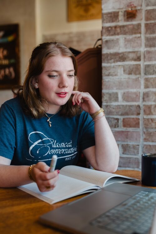 a CC Plus Masters Program student writing in a notebook